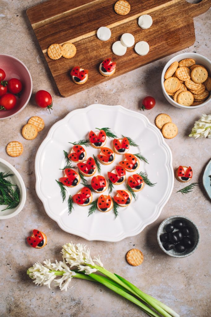 gustare pentru copii cu biscuiți sărați, roșii și brânză în formă de buburuze